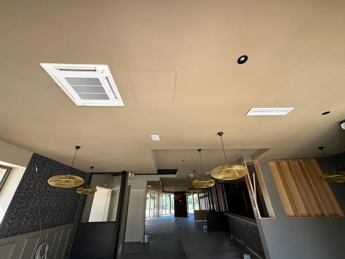 Salle du restaurant à Amiens sous plafond continu, suspensions et cassette de climatisation encastrée.