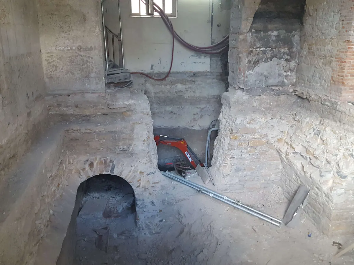 Caves en pierre et en brique sous l’Hôtel-Dieu de Lyon, une mini-pelle rouge au fond de la fouille.