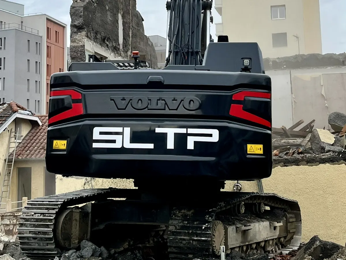 Pelle Volvo noire siglée SLTP sur les gravats du chantier Union Square, à Lyon 8.